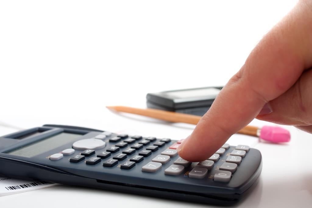 A finger adding up figures using a calculator isolated over a white background