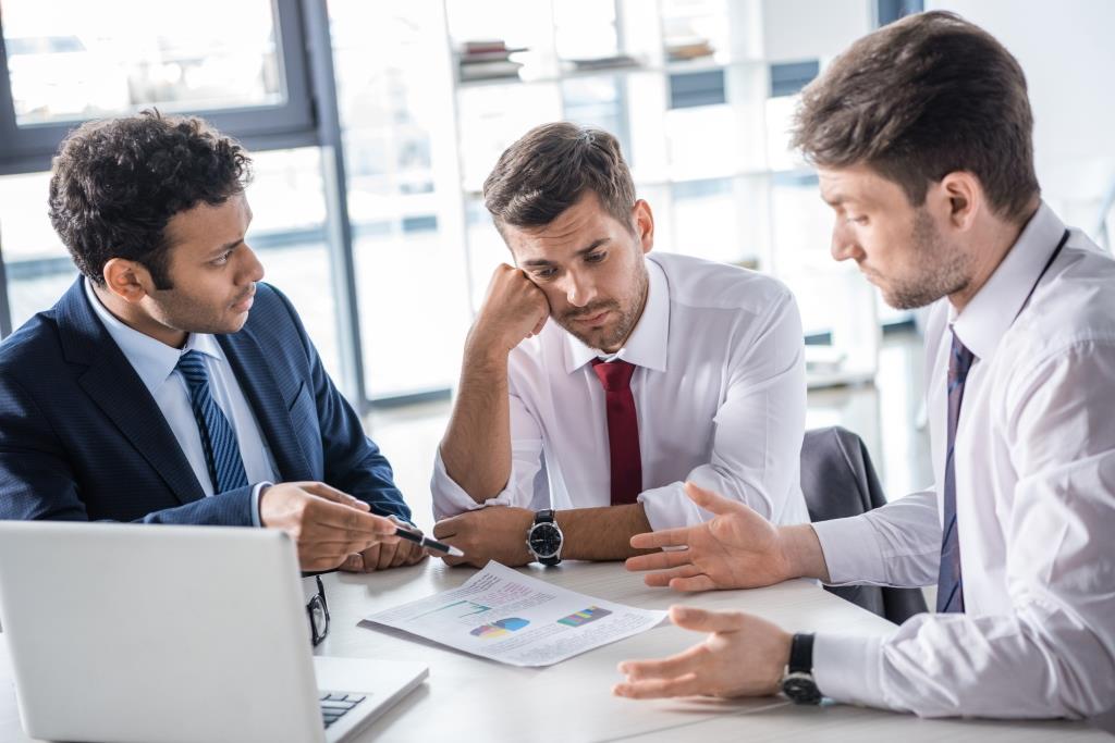 serious-business-people-sitting-at-table-and-discu-E7HTFA5