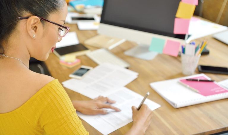 Businesswoman writing on document sitting in the office